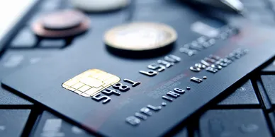 Close-up of a credit card with coins on top of a computer keyboard, symbolizing financial investigations or cyber fraud analysis